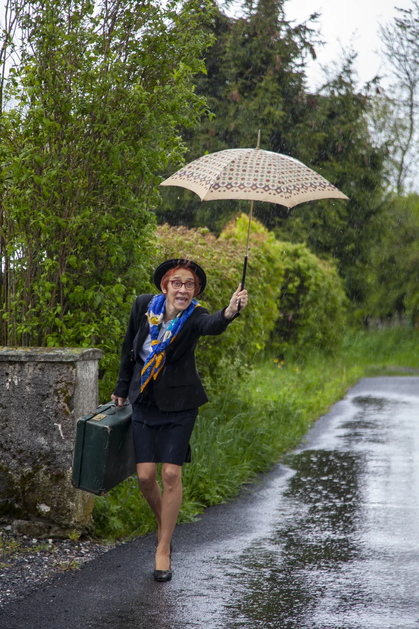 Guide-actrice de Muséâm sous la pluie, parapluie à la main lors d’un circuit dans le Chablais.