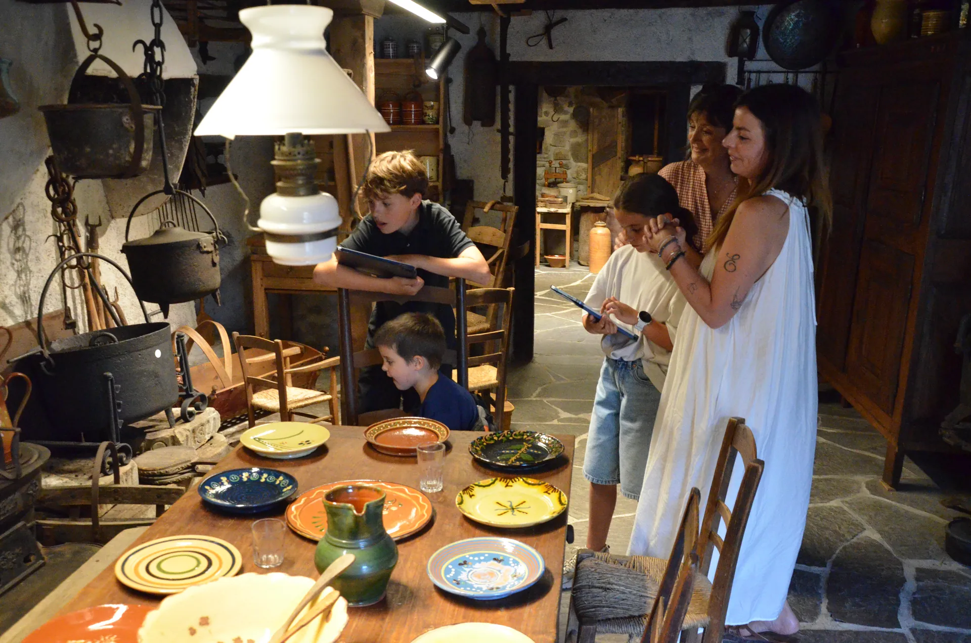 Une famille explore la cuisine traditionnelle du musée de Fessy avec le visioguide.